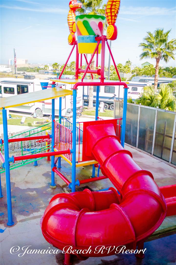 Colorful water play structure with slide and tipping bucket at Jamaica Beach RV Resort