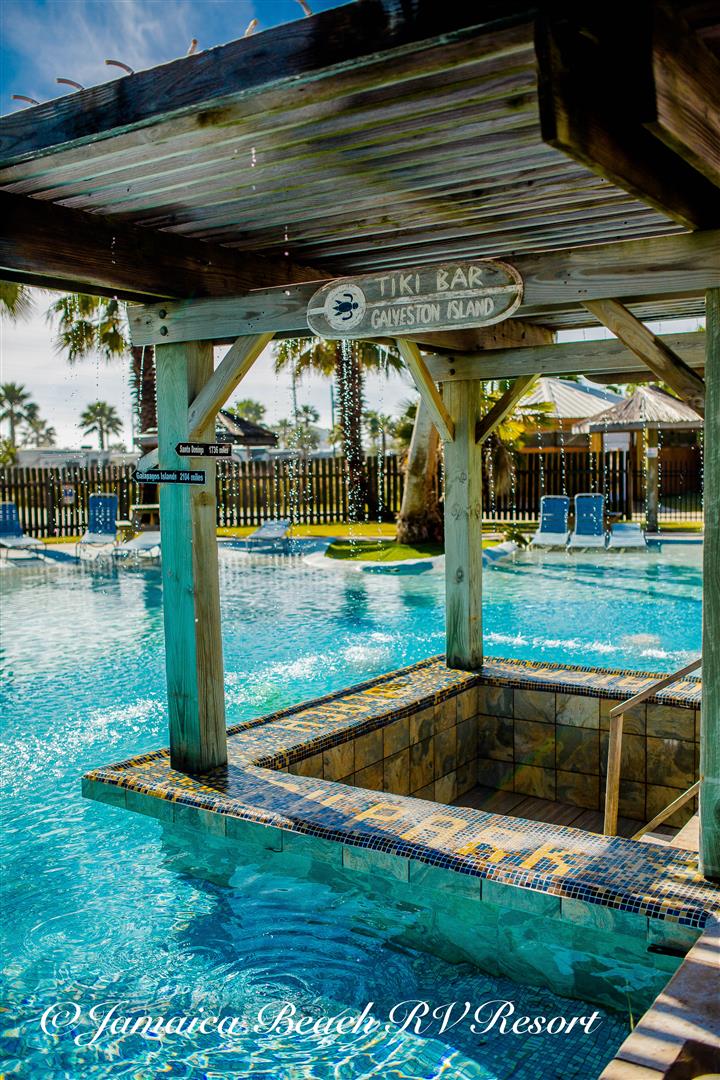 Tropical-themed pool area with a swim-up Tiki Bar at Jamaica Beach RV Resort on Galveston Island