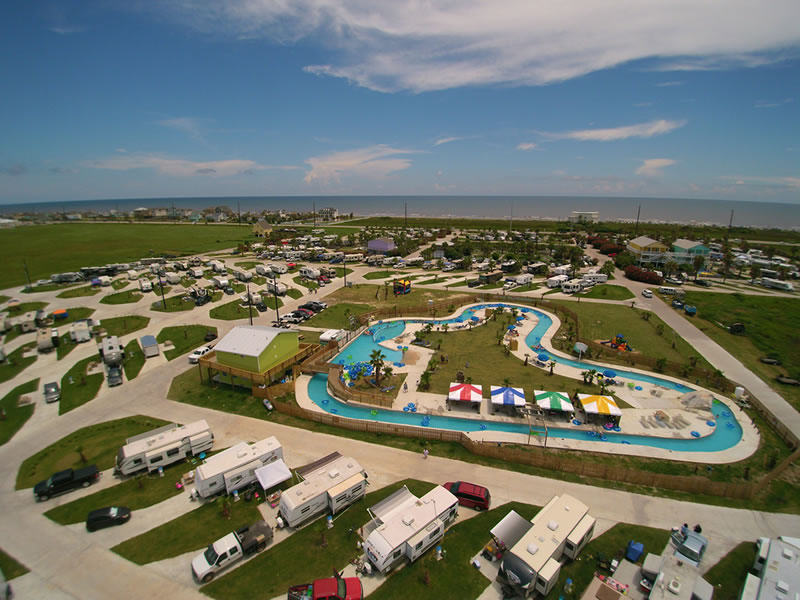 Guests floating along the lazy river at Jamaica Beach RV Resort, enjoying the sunshine and tropical landscape
