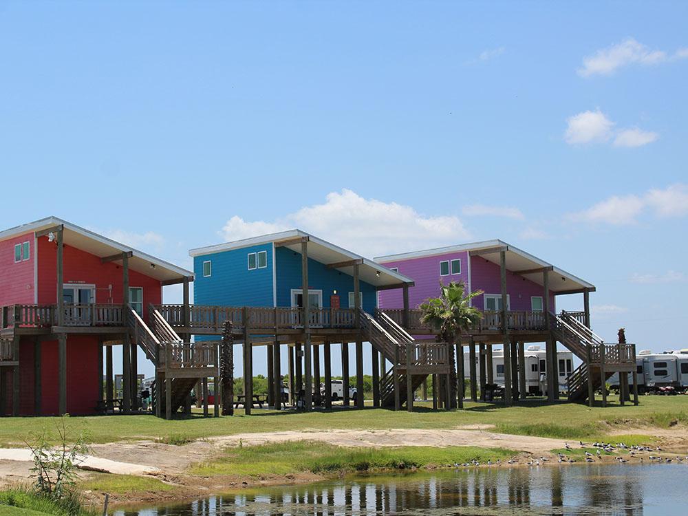Colorful elevated beach houses near RVs and palm trees at Jamaica Beach RV Resort
